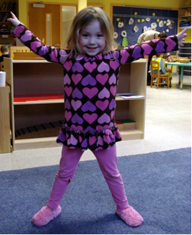 Child posing with arms in the air at yoga class